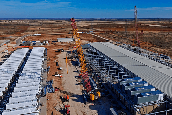 Aerial construction view shows data center structures BESS batteries red cranes and metal framing.