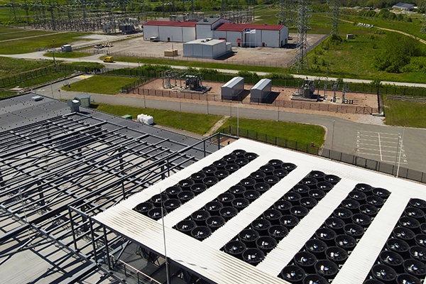Aerial view of a data center rooftop with large cooling fans and adjacent electrical substation, highlighting power infrastructure, HVAC climate control, and industrial-scale operations.